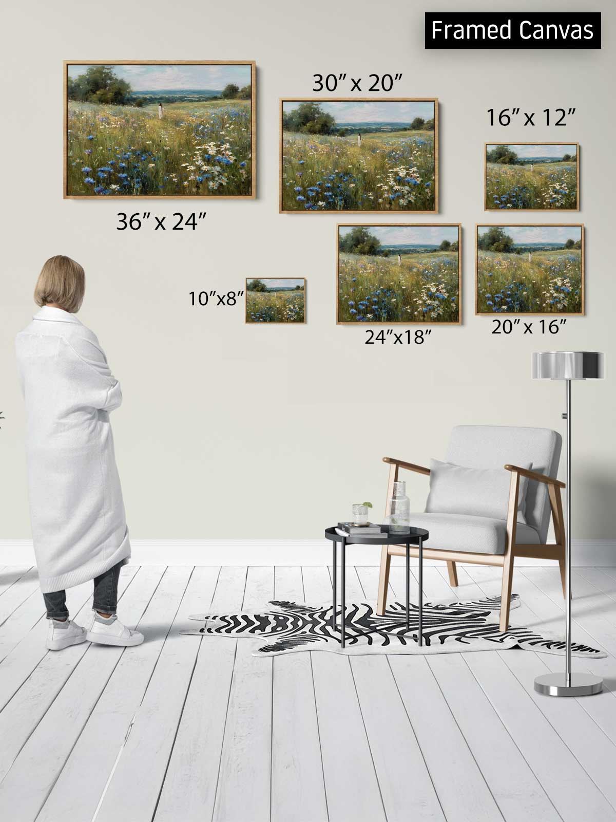 a person standing in a room, looking at a collection of framed landscape paintings on the wall. The paintings vary in size, with some being larger than others. The person appears to be examining the artwork, possibly appreciating the different sizes and details of the paintings.