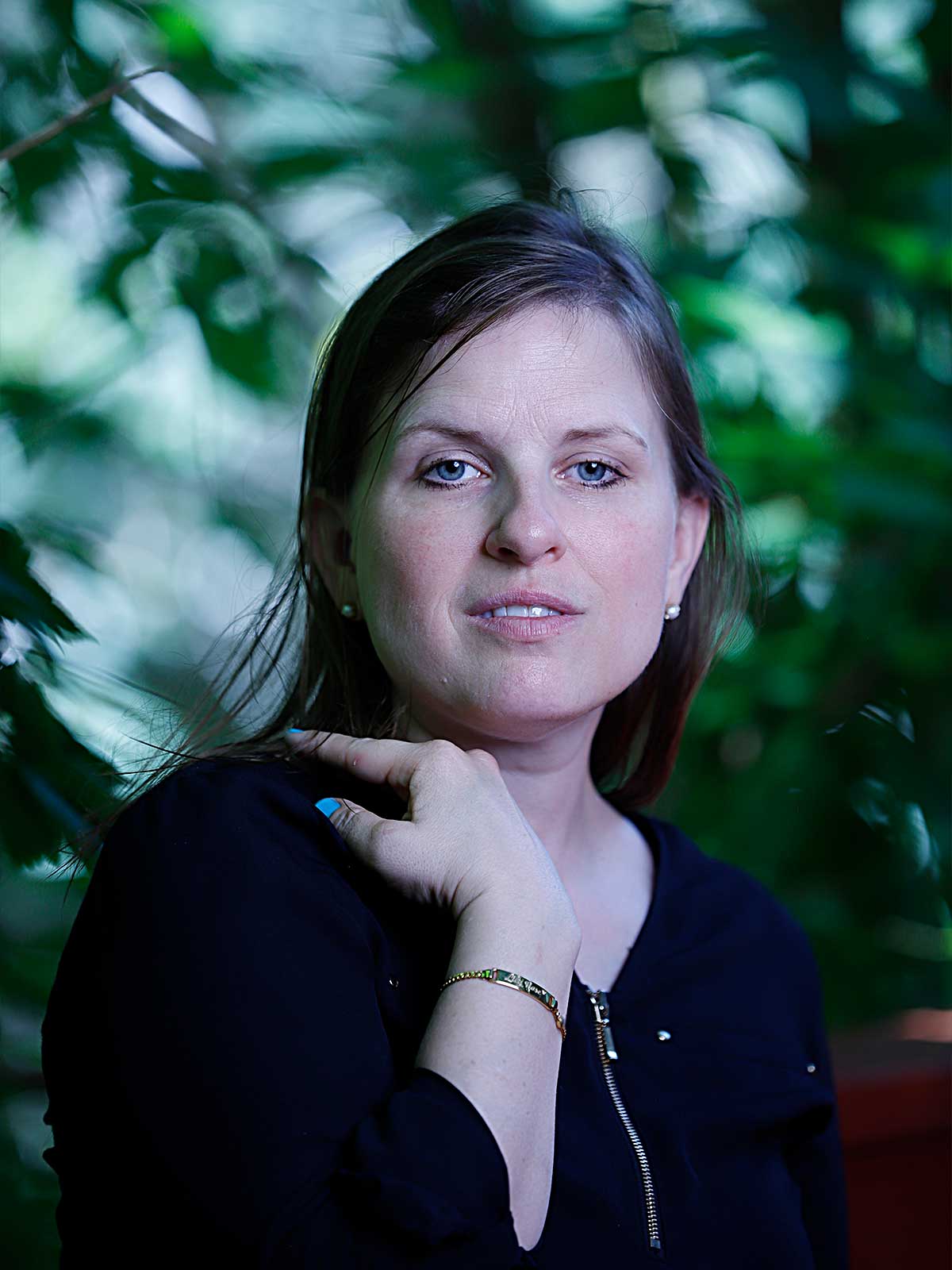 a woman is posing for a picture in front of a tree