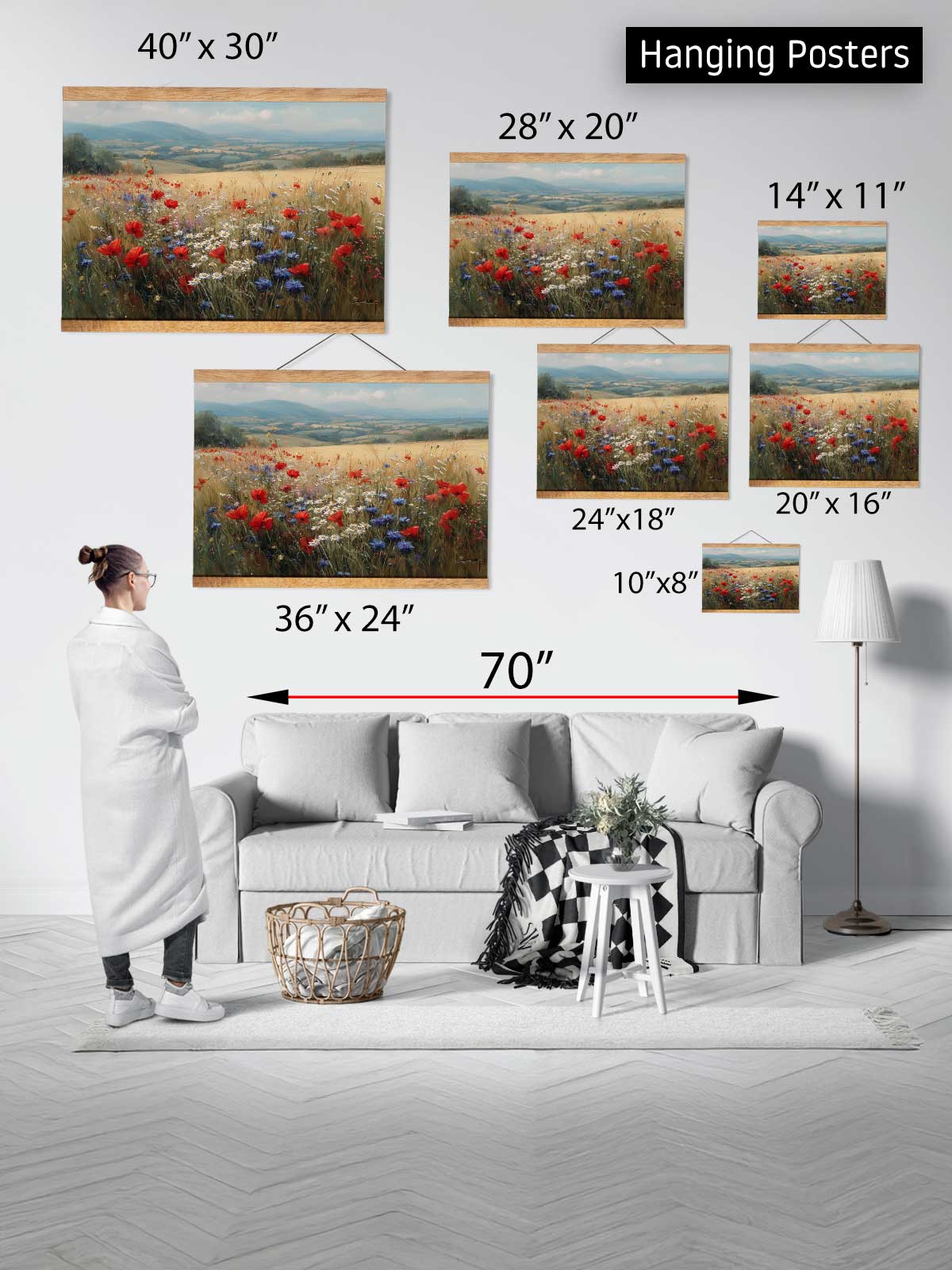 a person standing in a living room, surrounded by various sizes of hanging posters depicting landscapes, including a field of flowers. The posters are arranged on the wall, with the largest one spanning 70 inches in width. The person appears to be observing the posters, which are displayed in a collage format.
