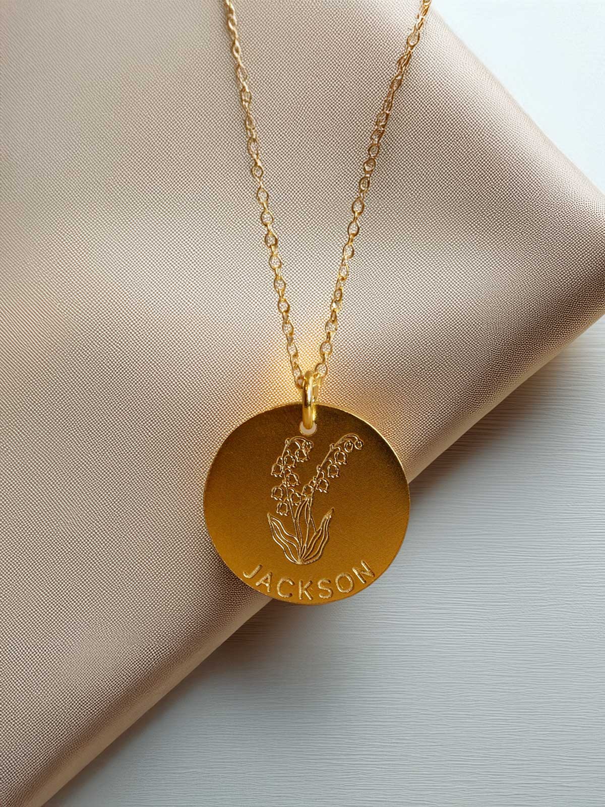 a gold necklace with a flower engraved on it