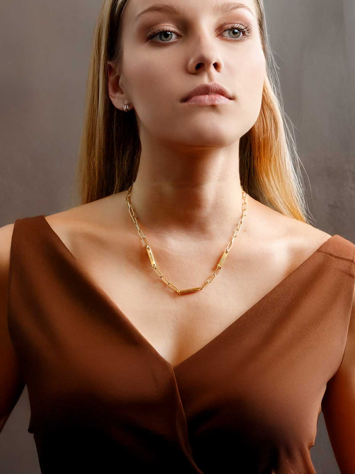 a woman in a brown dress wearing a gold necklace