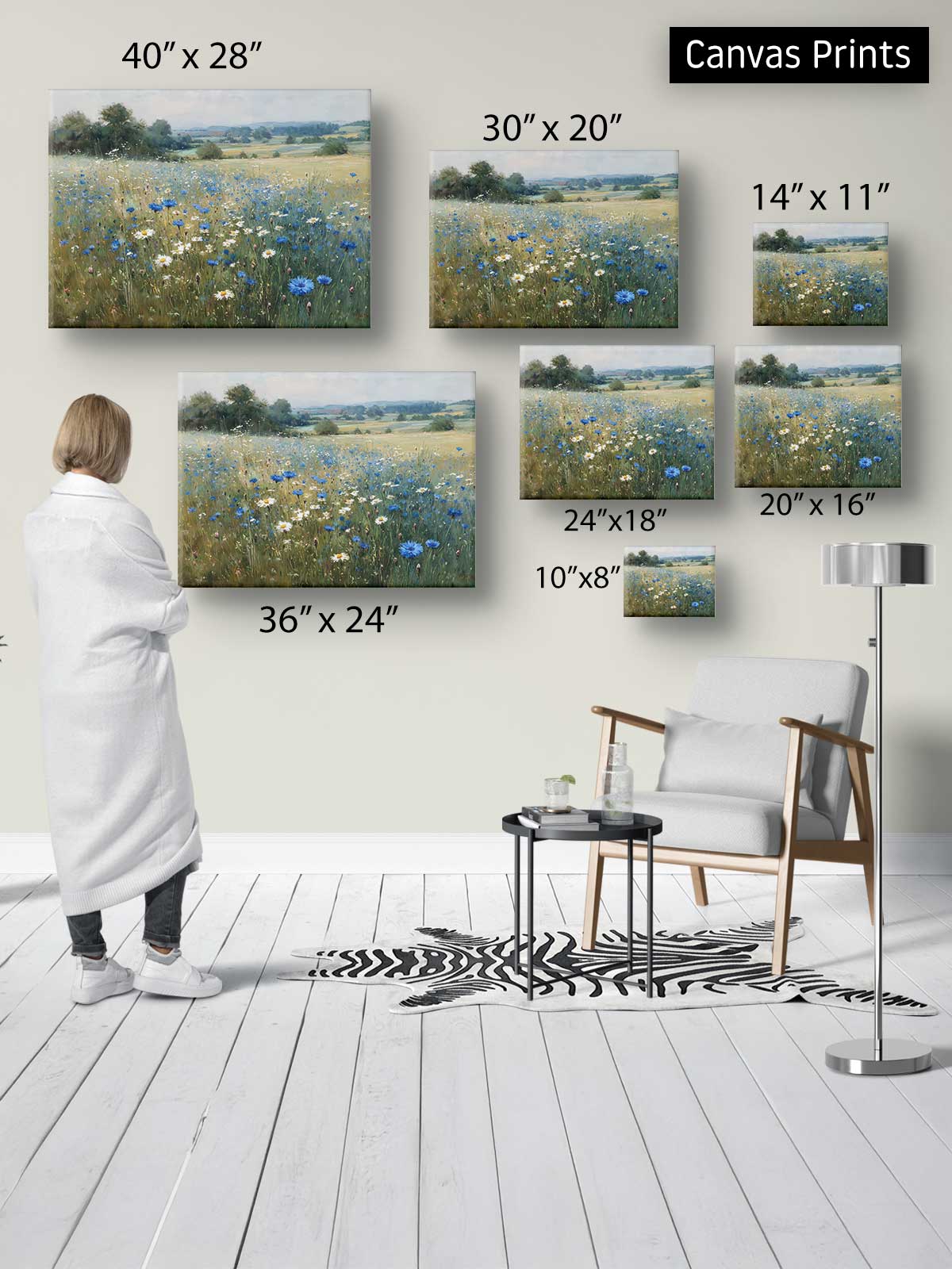 a person standing in a room, looking at a wall with various sizes of paintings or canvas prints displayed on it.