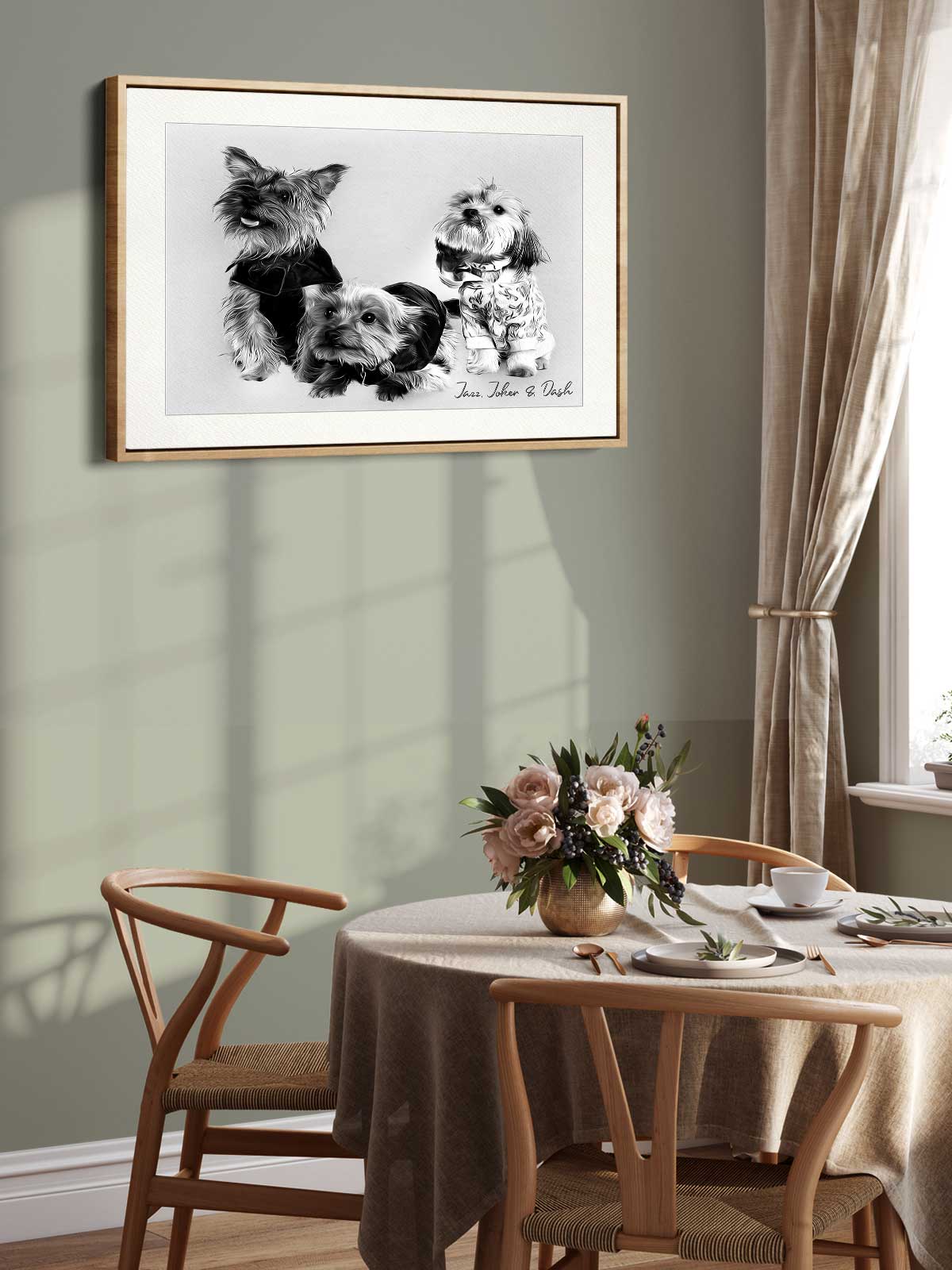 a framed black and white photograph of three dogs, with a vase of flowers on a table in front of it. The photograph is hanging on a wall above a wooden table with chairs.