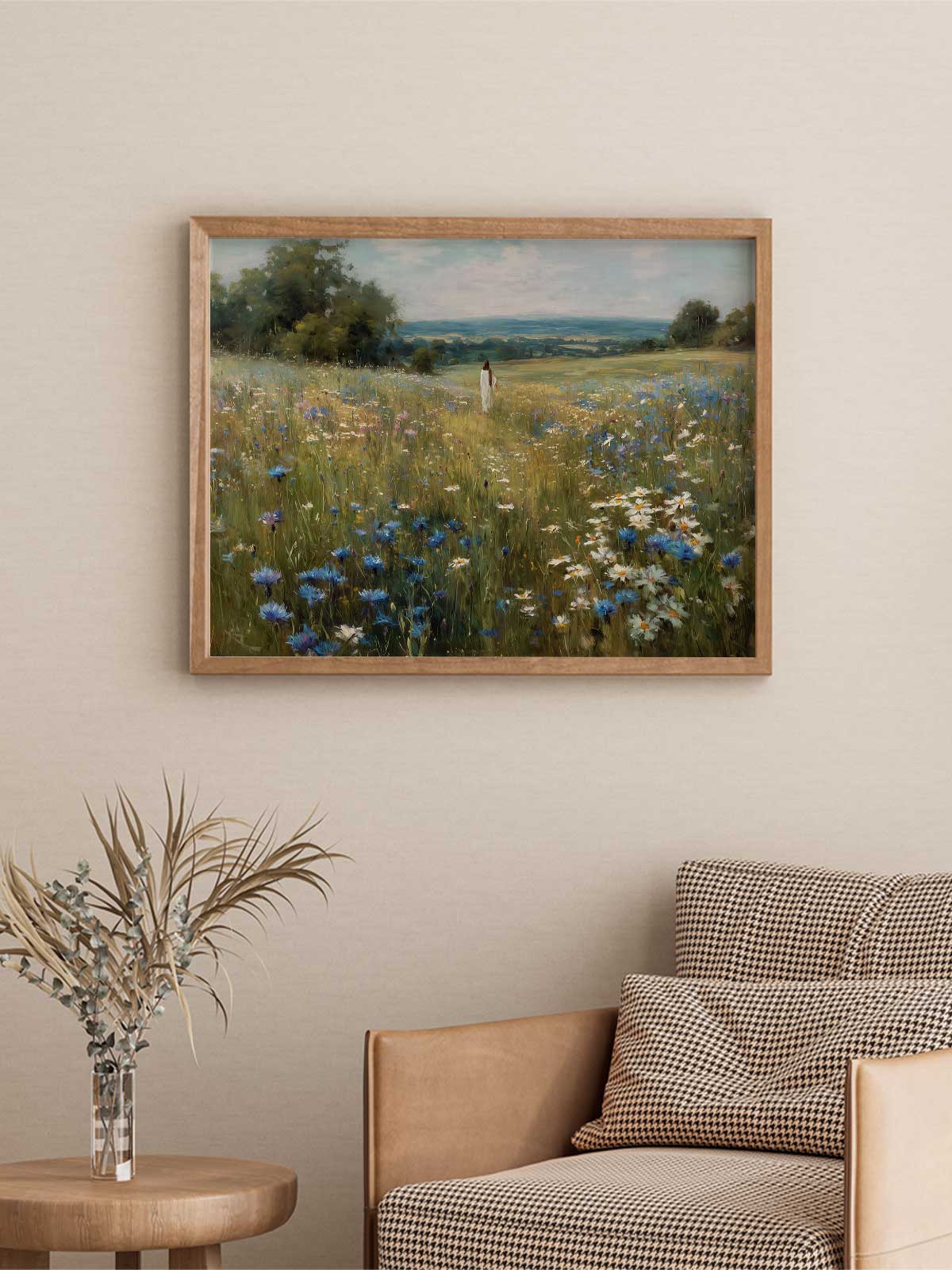 a painting of a field with flowers hanging on a wall above a brown armchair in a living room setting.