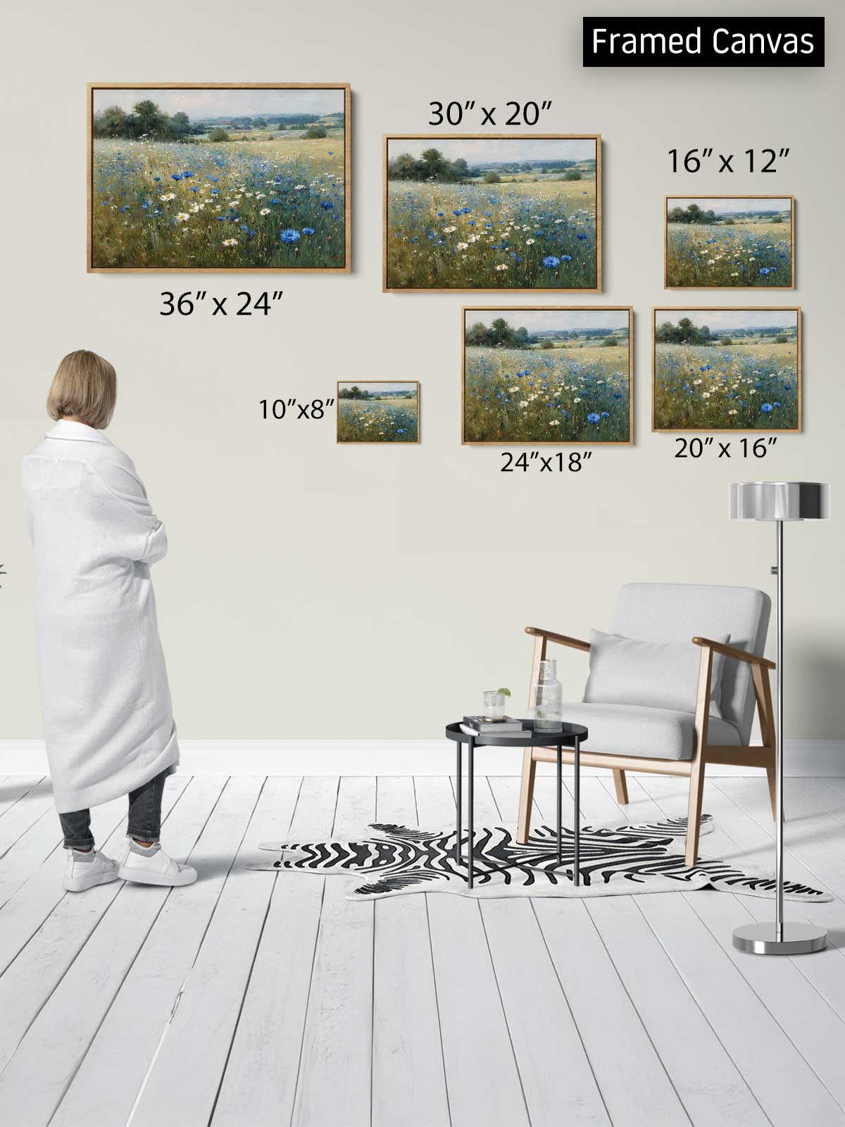 a person standing in a room, surrounded by framed paintings of a field of flowers. The paintings vary in size, ranging from 36" x 24" to 20" x 16". The person appears to be observing the artwork, which is displayed on the wall in a framed canvas format.