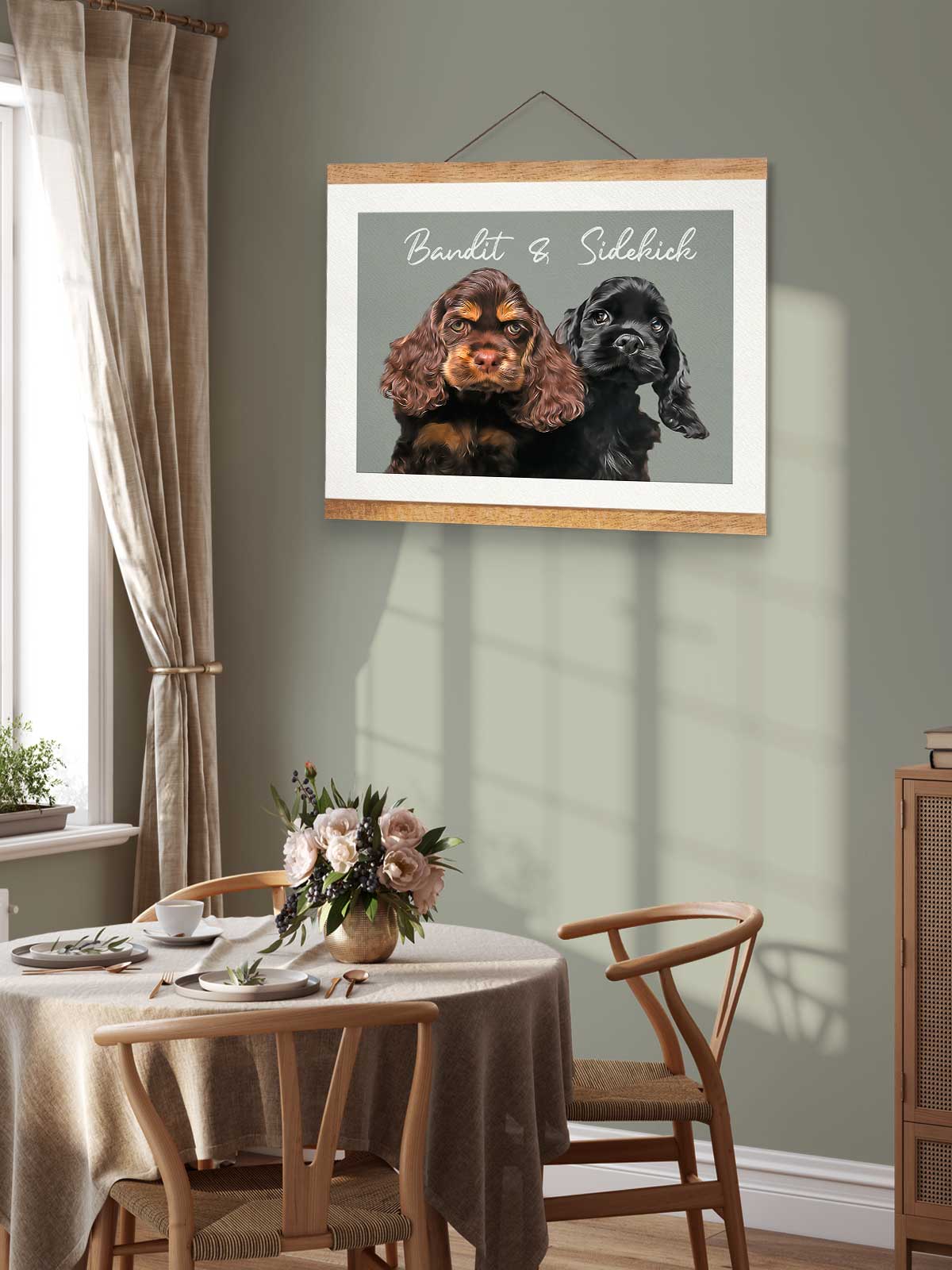 a framed photograph of two dogs, one black and one brown, hanging on a wall above a wooden table with a vase of flowers.