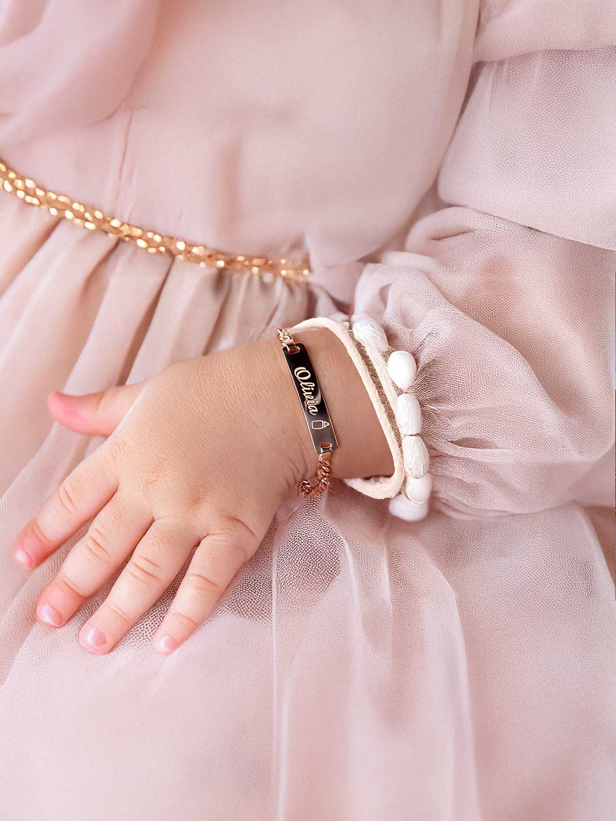 a little girl in a pink dress holding onto a bracelet