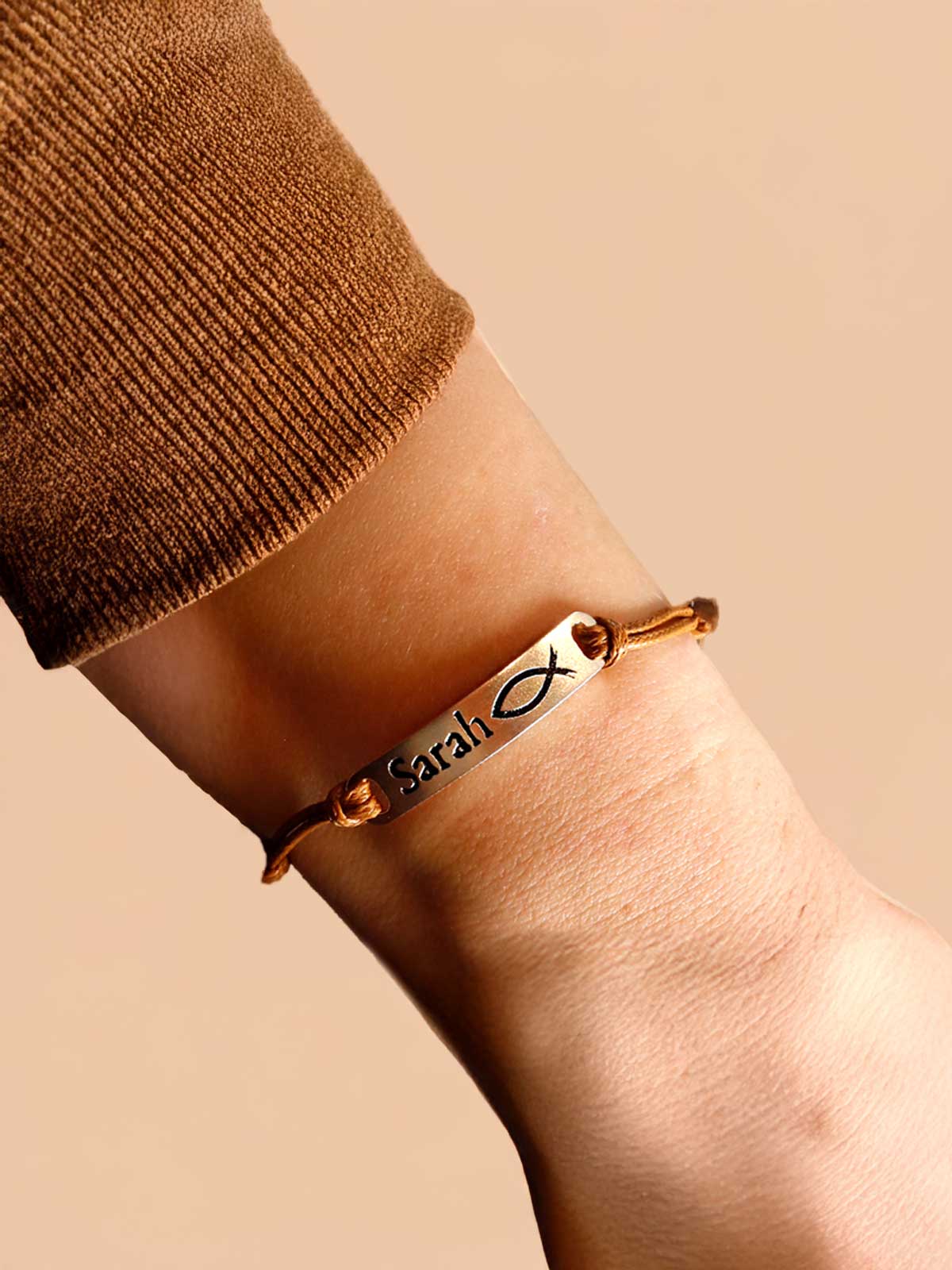 a person wearing a gold bracelet with a fish charm