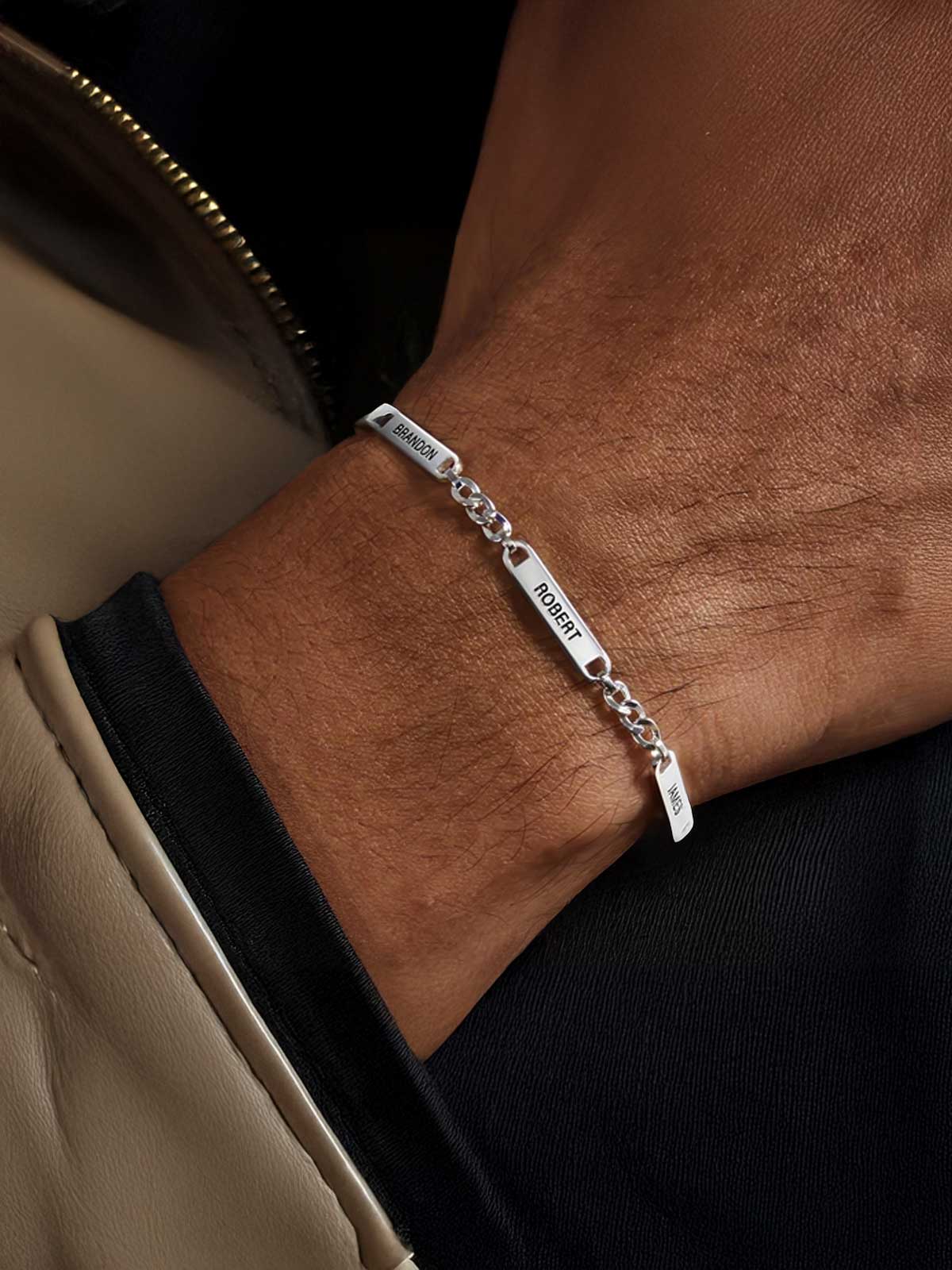 a man wearing a silver bracelet with a name on it