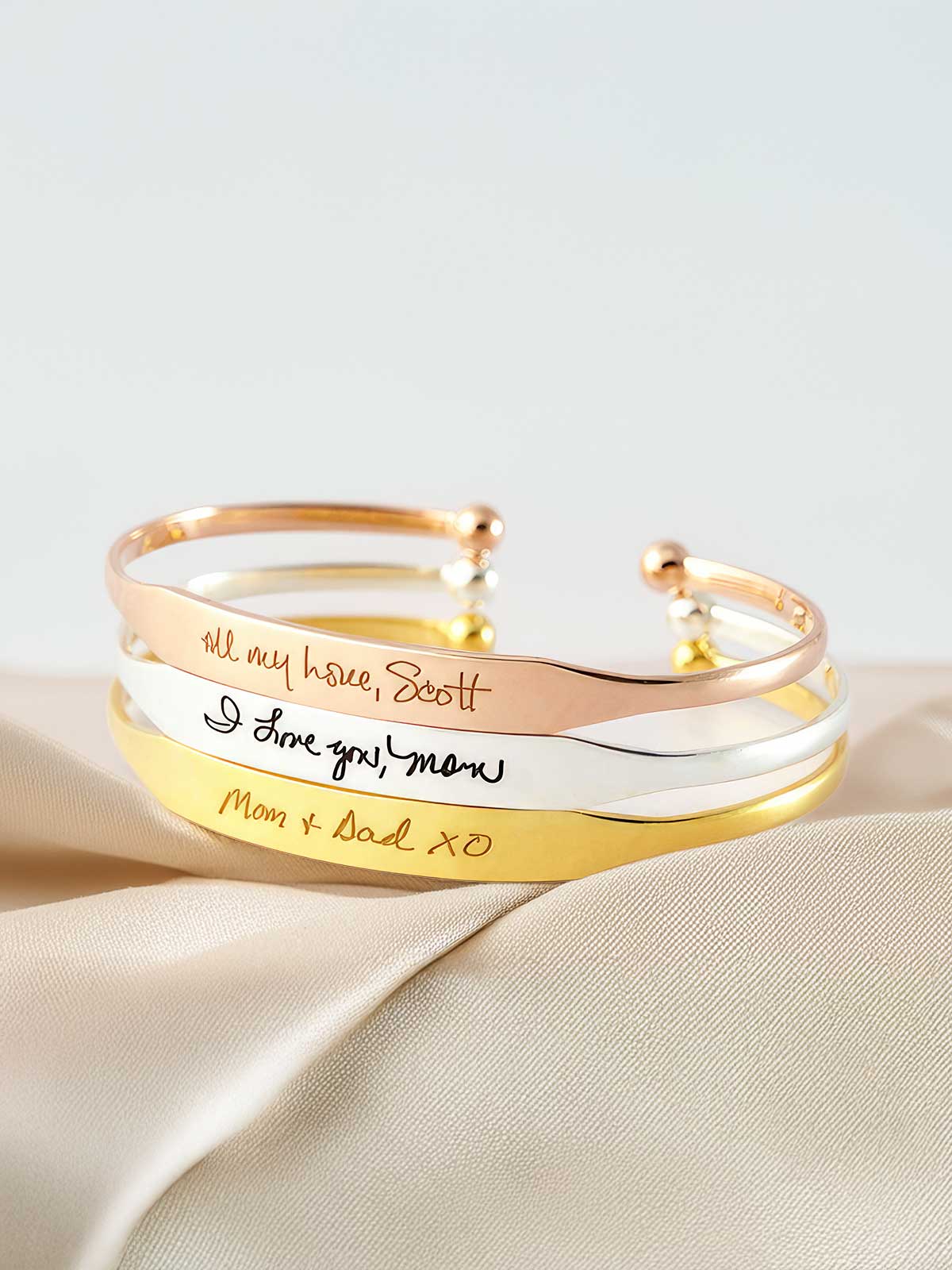 three gold and silver bracelets with handwriting on them