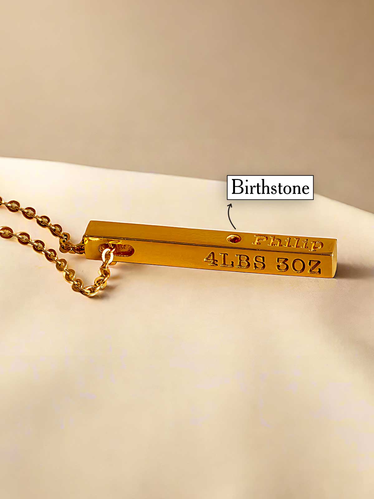 a close up of a gold necklace with a name tag on it