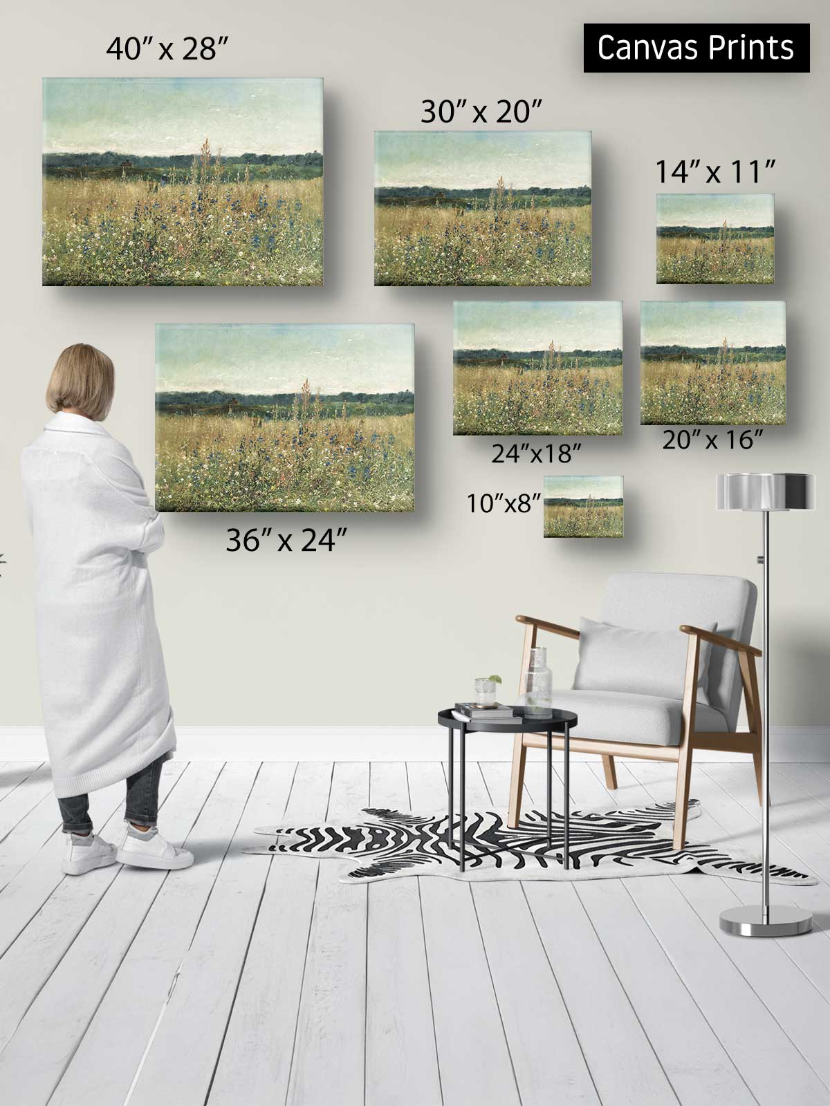 a person standing in a room, surrounded by various sizes of landscape paintings displayed on the wall.