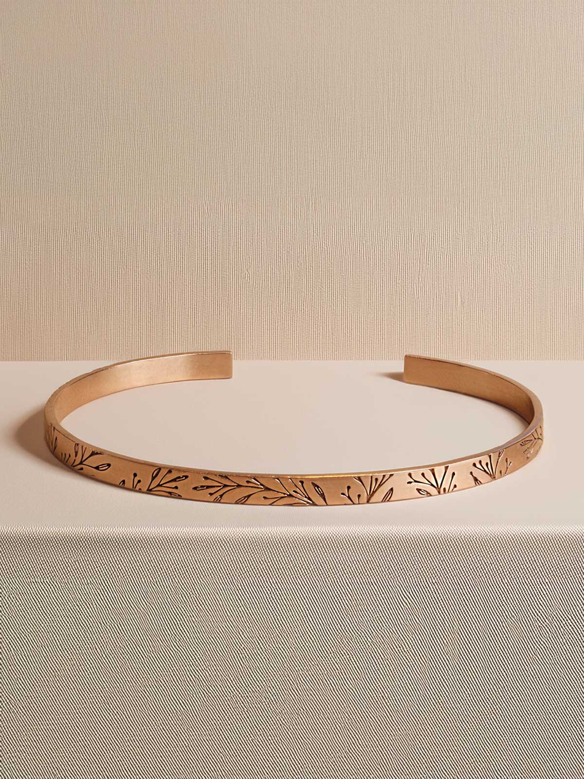 a close up of a gold bracelet on a white surface