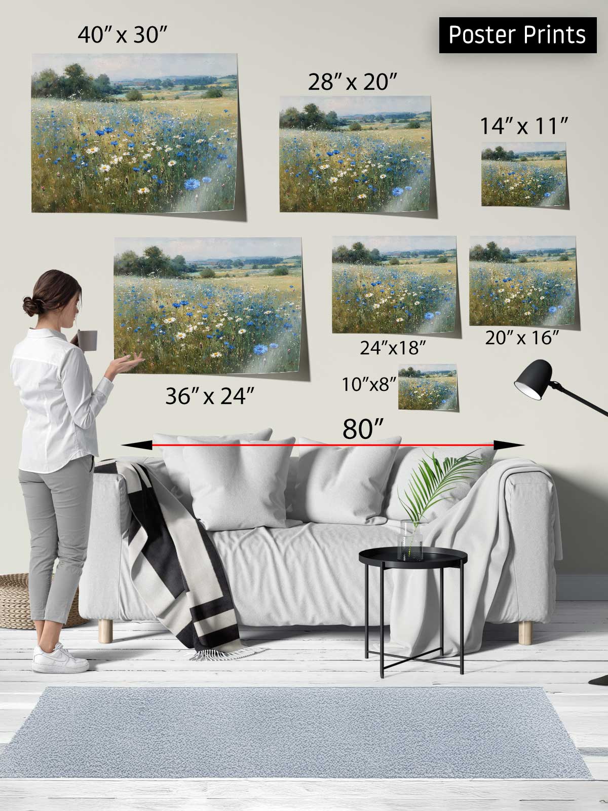 The image is a poster print display featuring a woman standing in front of a couch, with various sizes of the same landscape painting displayed above her.