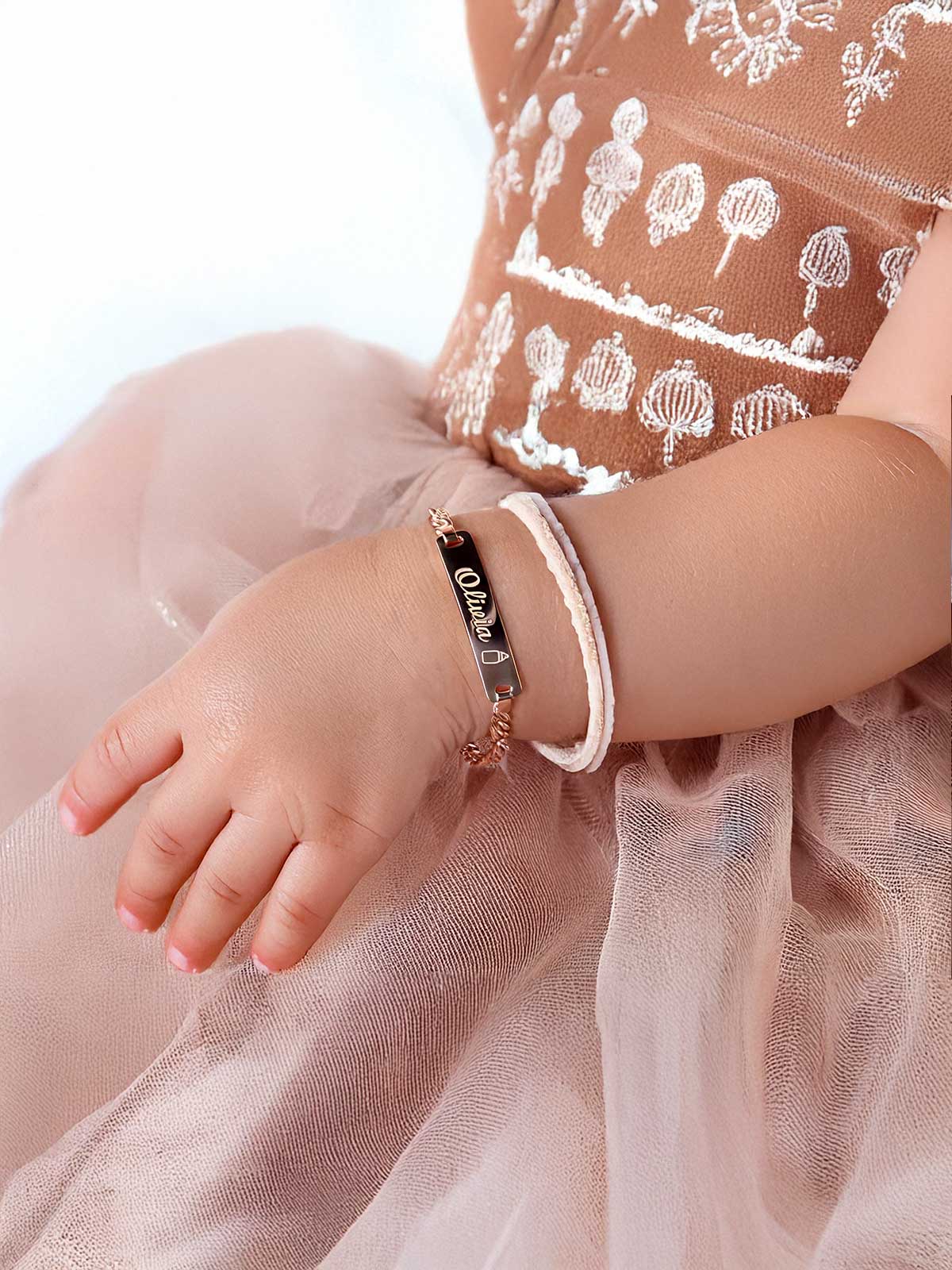 a little girl wearing a bracelet and a dress