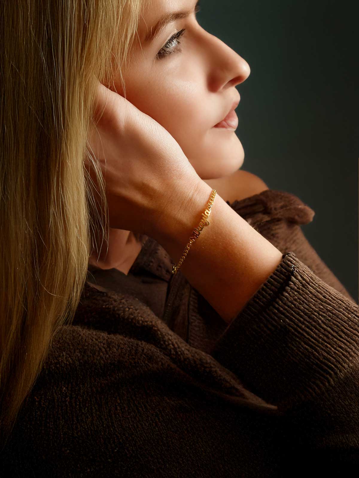 a woman wearing a gold bracelet and a brown sweater