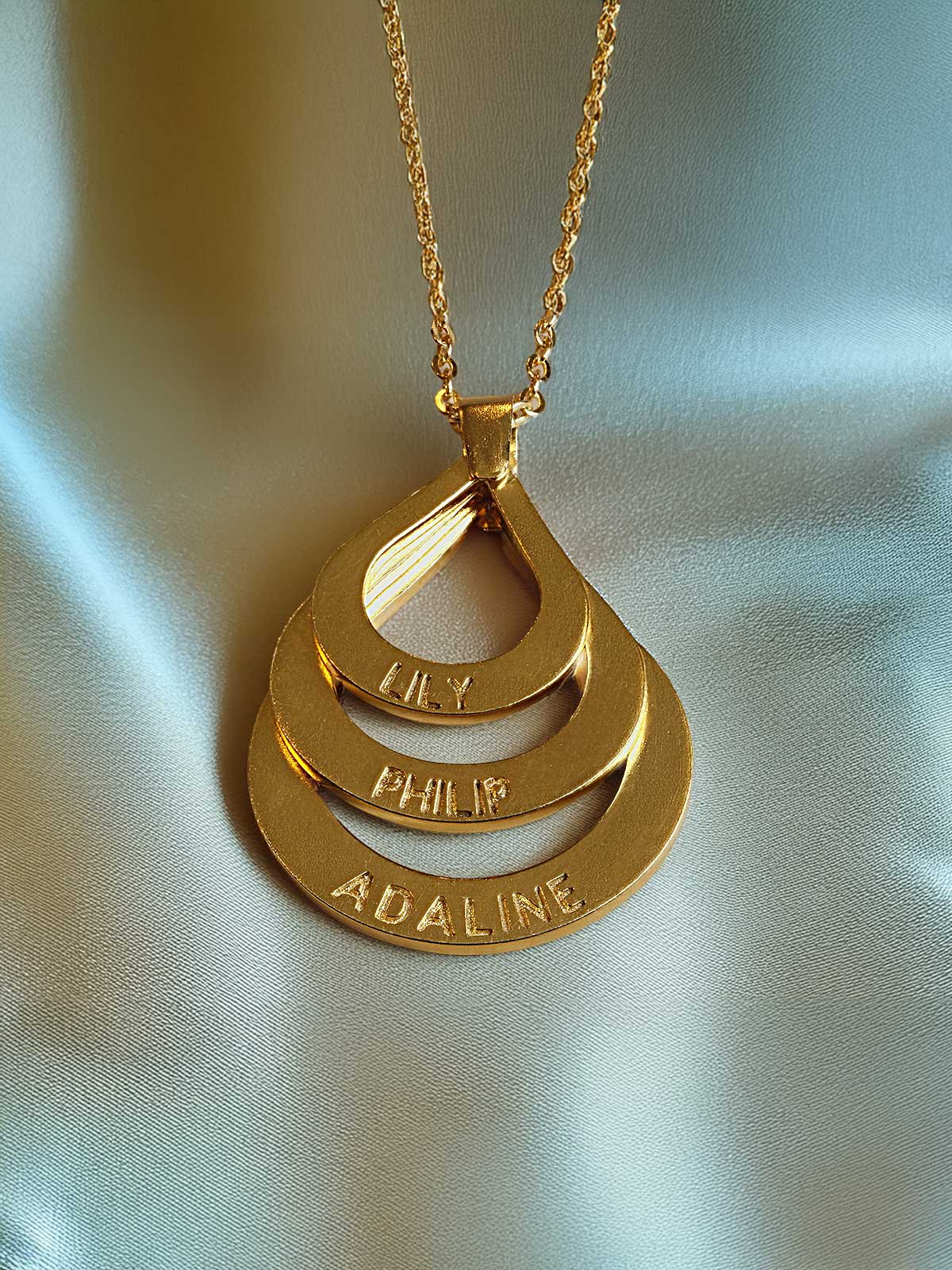 a gold plated necklace with three names on it